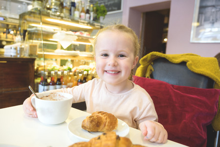 Beautiful young girl at the bar eating breakfast.の写真素材