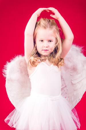 Beautiful blond hair angel on a red backgroundの写真素材