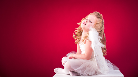 Beautiful blond hair angel on a red backgroundの写真素材