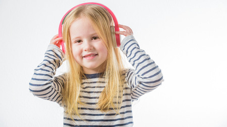 Little happy girl listening music on headphonesの写真素材