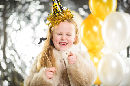 Little beautiful girl at a party New Year with balloons.
