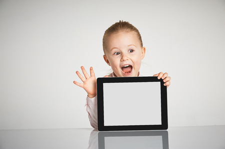 Cute little and smiling girl plays with a tabletの写真素材