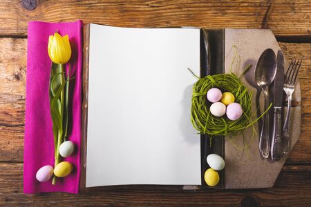 Easter menu on a wooden table decorated in eggs and fresh flowers.の写真素材