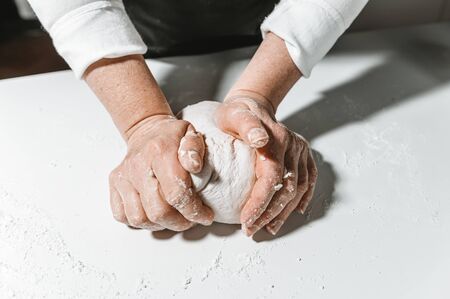 Kneading and preparing the dough by woman's hands on the tableの写真素材