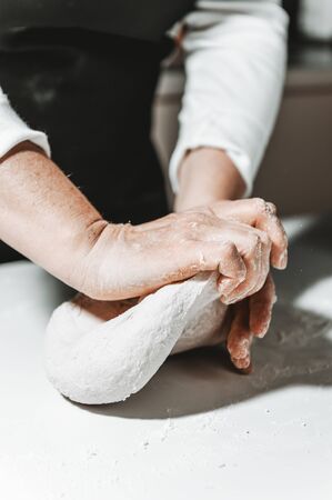 Kneading and preparing the dough by woman's hands on the tableの写真素材