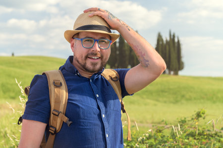 Young beautiful man Hiking in Tuscany and Italian medieval towns with a backpack