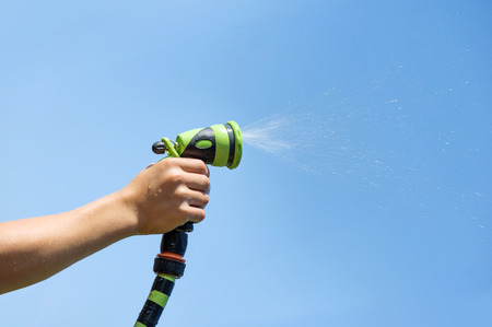 Hand holding water sprinkler against blue sky, irrigatingの写真素材