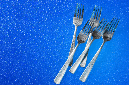 A group of dinner forks. Blue background with kitchen utensil