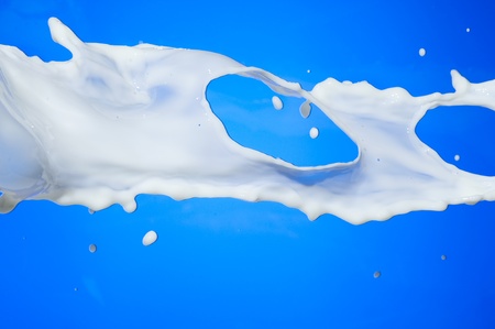 Splashing milk on blue background. Pouring milkの写真素材