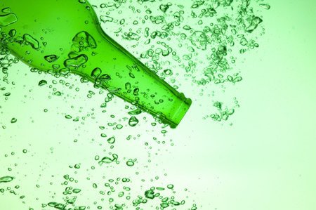 Green bottle with creative splashing green waterの写真素材