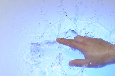 Hahd with plastic bottle in blue water