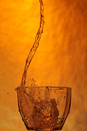 Whisky and ice. Splashing scotch on brown backgroundの写真素材
