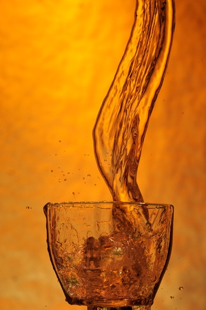 Whisky and ice. Splashing scotch on brown backgroundの写真素材