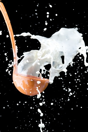 Scoop and splashing milk on black background. Pouring milk
の写真素材