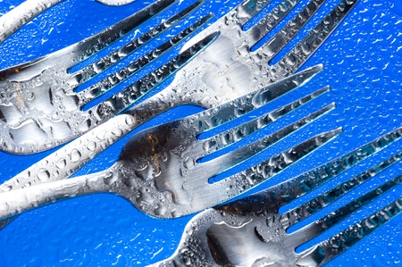 A group of dinner forks. Blue background with kitchen utensilの写真素材