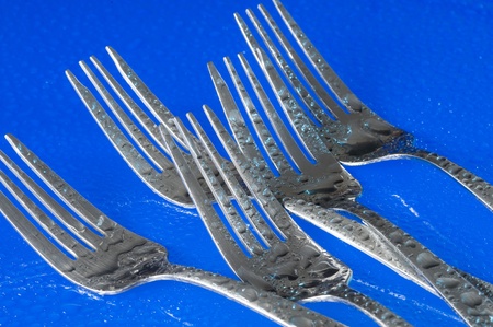 A group of dinner forks. Blue background with kitchen utensilの写真素材