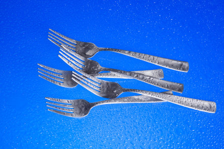 A group of dinner forks. Blue background with kitchen utensil