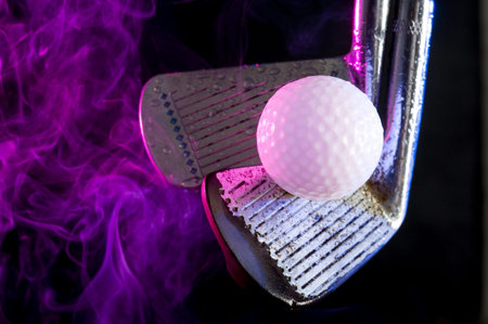 Old golf clubs with  ball on black background