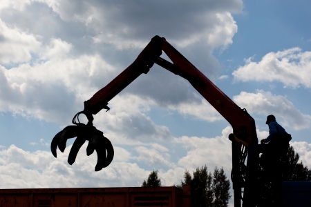 Silhouette of worker using hydraulic grabbler armの写真素材