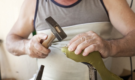 a cobbler, hammering a nail to glue the sole of the shoeの写真素材