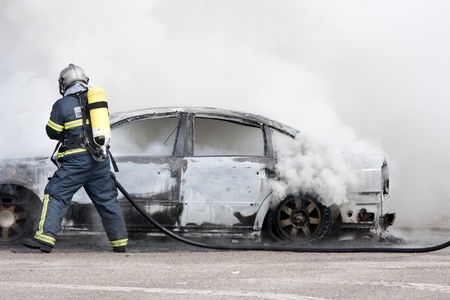 a firefighter putting out a car that was burningの写真素材