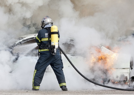 a firefighter putting out a car that was burningの写真素材