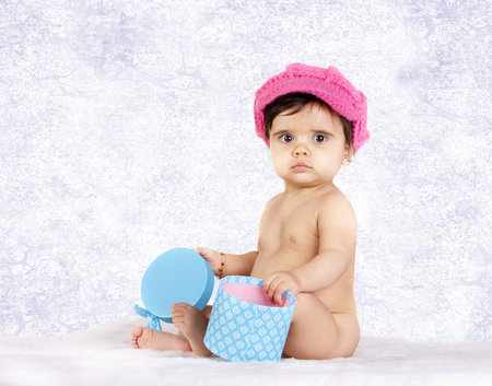 a baby with a pink hat and a gift box