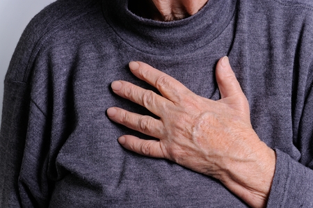 elderly woman with hand on her chestの写真素材