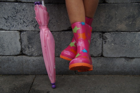 Cute kid legs with legs in rubber boots holding a umbrellaの写真素材