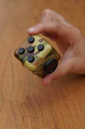 Child hand holding a fidget cubeの写真素材