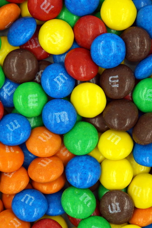Pile or button-shaped M & M chocolates background. M & M's is a product of the Mars Wrigley Confectionery division of Mars, Incorporated. Pile or button-shaped M & M chocolates background. M & M's is a product of the Mars Wrigley Confectionery division of Mars, Incorporated.