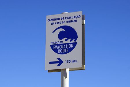 Faro, Portugal - December 24, 2019: Portuguese tsunami evacuation route sign against a clear blue sky.のeditorial素材