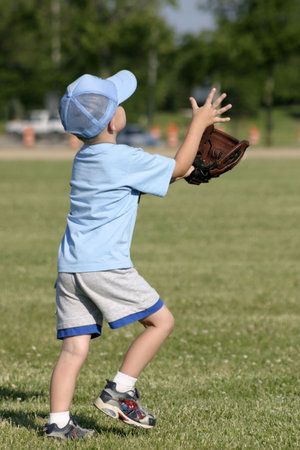 Young boy attempting to catch a fly ball