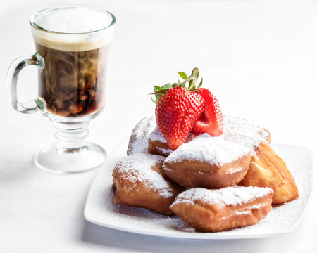 A plate of homemade beignets and coffee with milkの写真素材