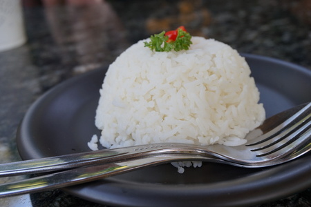 cooked rice with a spoon and fork on black plateの写真素材