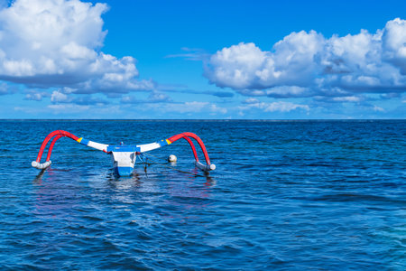 A small fishing boat is navigating the open sea with blue sky and white cloudsの写真素材