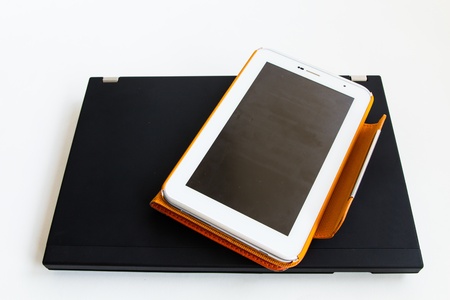 Tablet in orange case put on laptopの写真素材