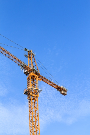 yellow hoisting crane and blue sky backgroundの写真素材