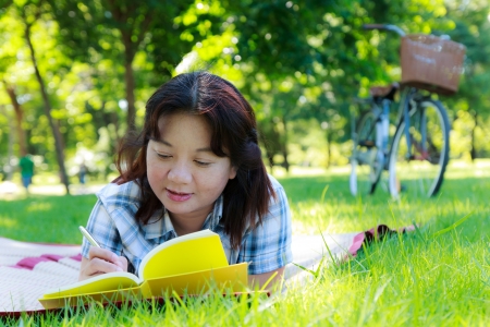 Asian woman with yellow book in the parkの写真素材