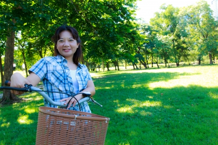 Asian woman with bicycle in the parkの写真素材