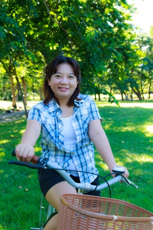 Asian woman with bicycle in the parkの写真素材