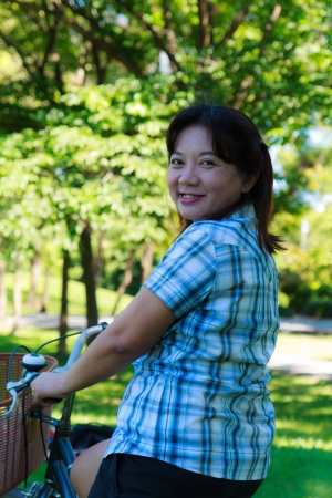 Asian woman with bicycle in the parkの写真素材