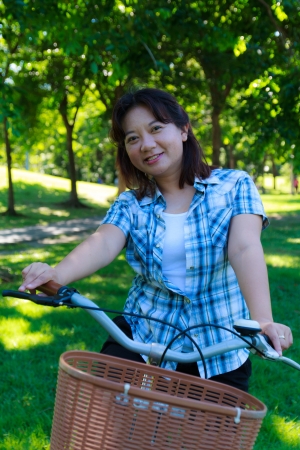 Asian woman with bicycle in the parkの写真素材