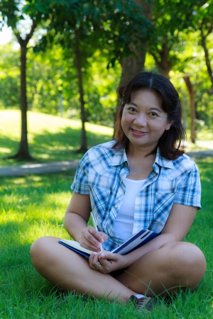 Asian woman writing diary in the parkの写真素材