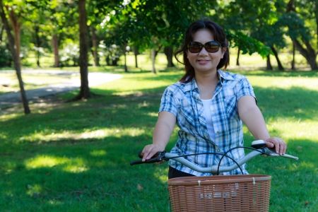 Asian woman with bicycle in the parkの写真素材