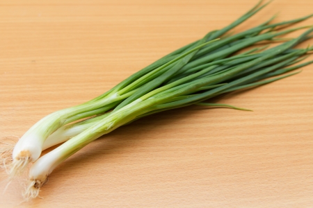 Spring onions or green onions on wooden tableの写真素材