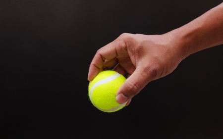 Hand put tennis ball isolated on blackの写真素材