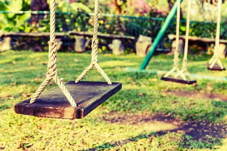 Vintage of wooden swing with green grass background in the parkの写真素材