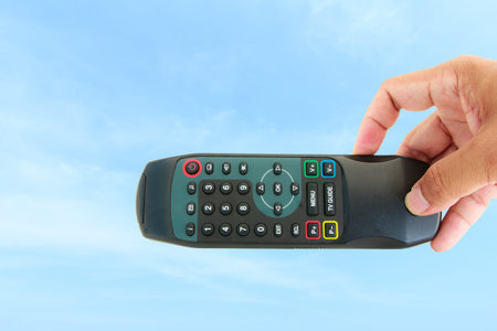 Hand show remote control on sky background