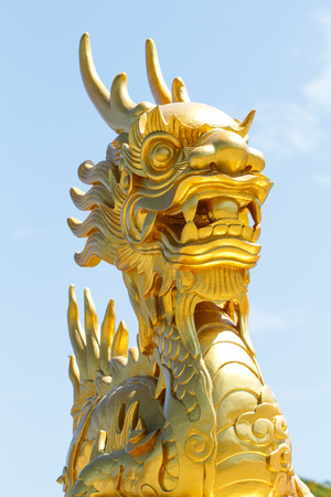 Golden dragon statue with blue sky backgroundの写真素材